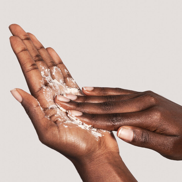 Model using ILUMA Intense Brightening Exfoliating Powder on hand