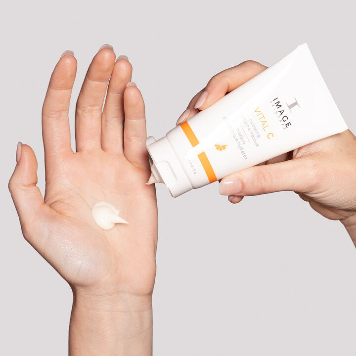 Model squeezing VITAL C Hydrating Enzyme Masque onto hand