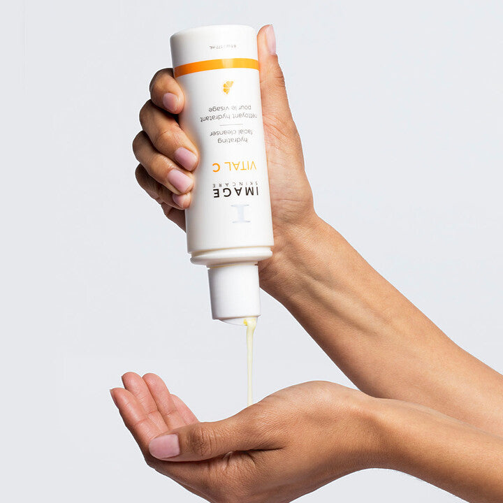 Model squeezing VITAL C Hydrating Facial Cleanser on to hand
